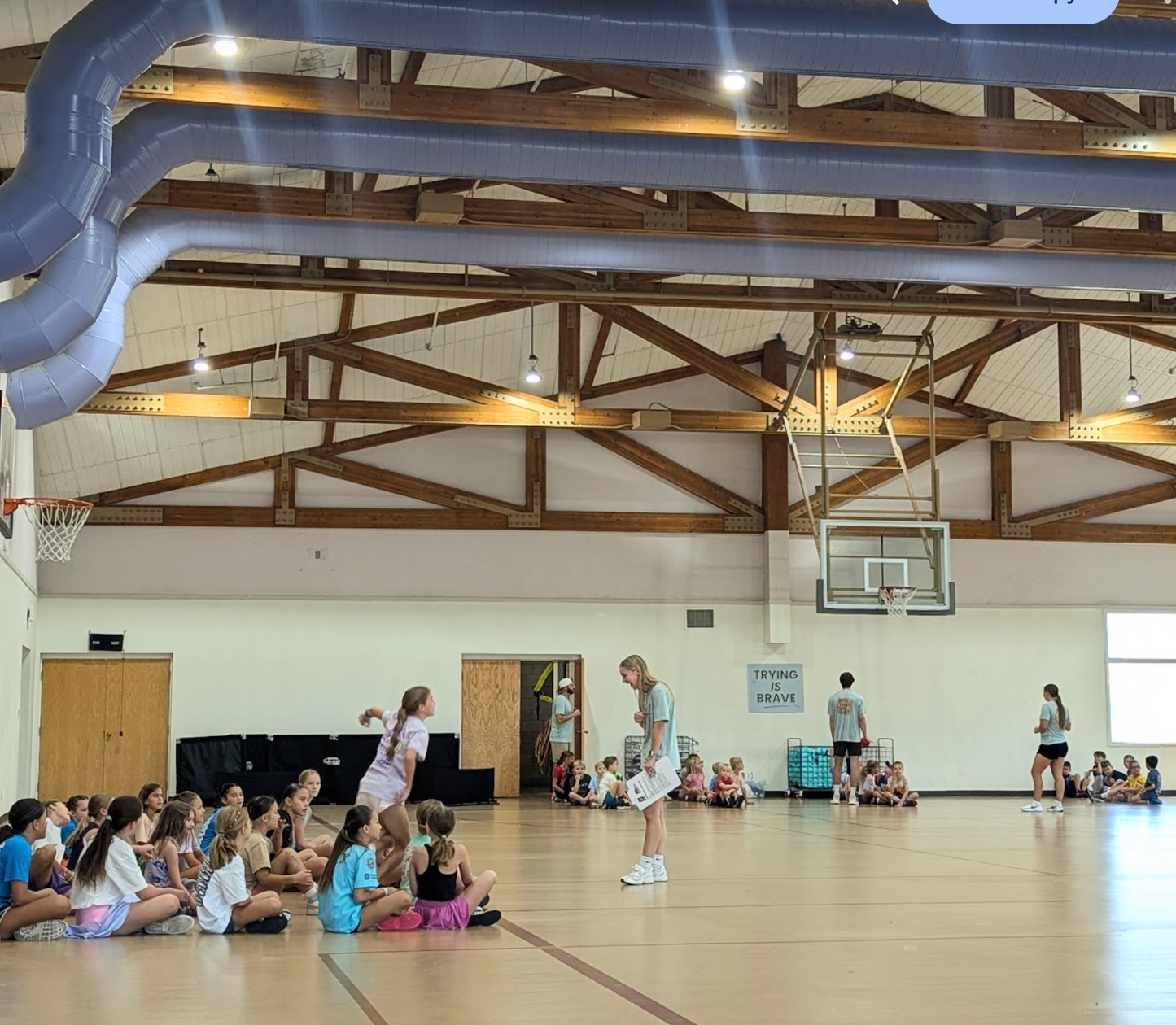 Group of children and adults in a gymnasium with basketball hoops.
