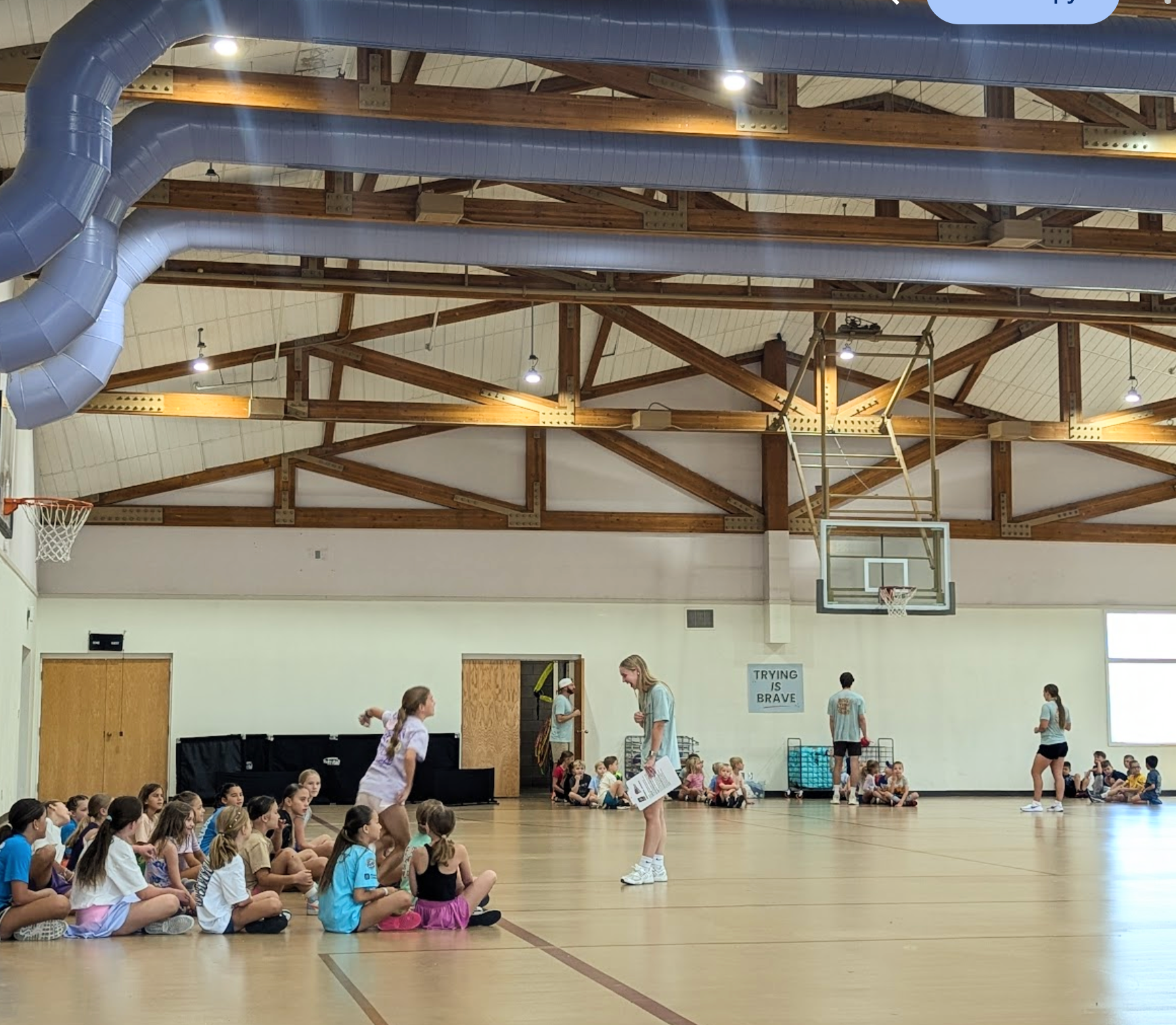 Group of children and adults in a gymnasium with basketball hoops.
